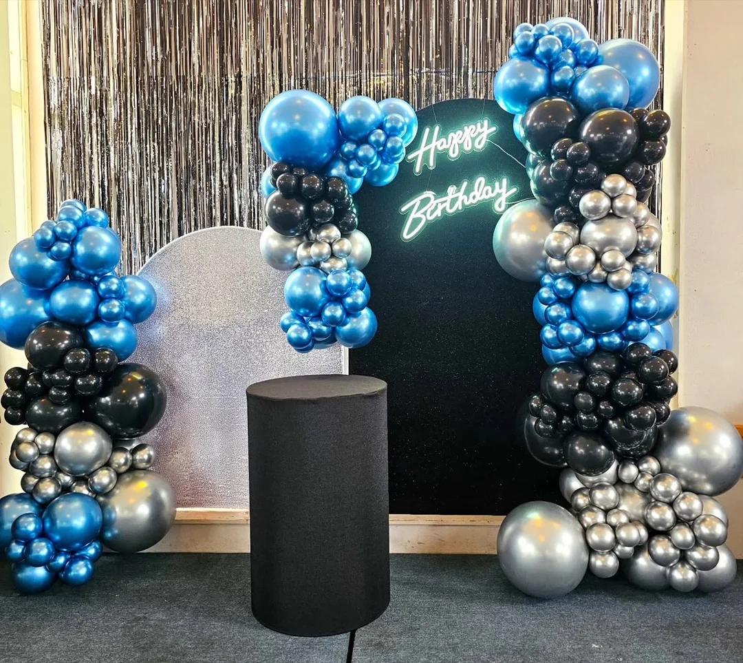 Blue, silver and black balloon backdrop with a Happy Birthday neon sign