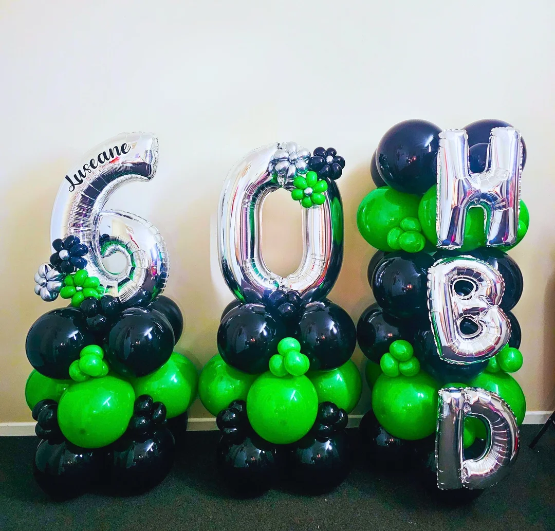 Three black and green balloon columns with silver 60 foil numbers, a personalised name and silver H B D foil letters