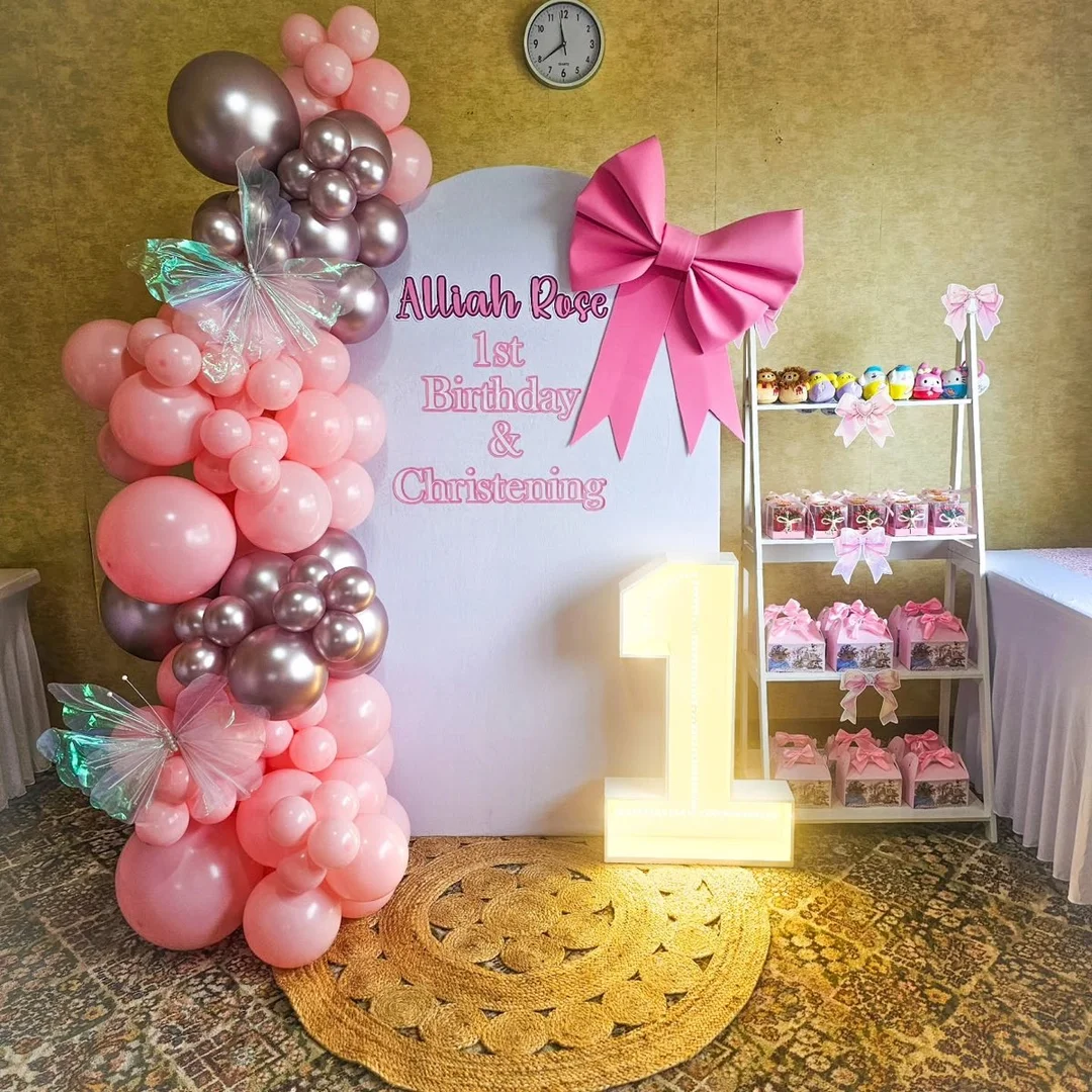 Pink and rose gold balloon garland around a personalised 1st birthday and christening board