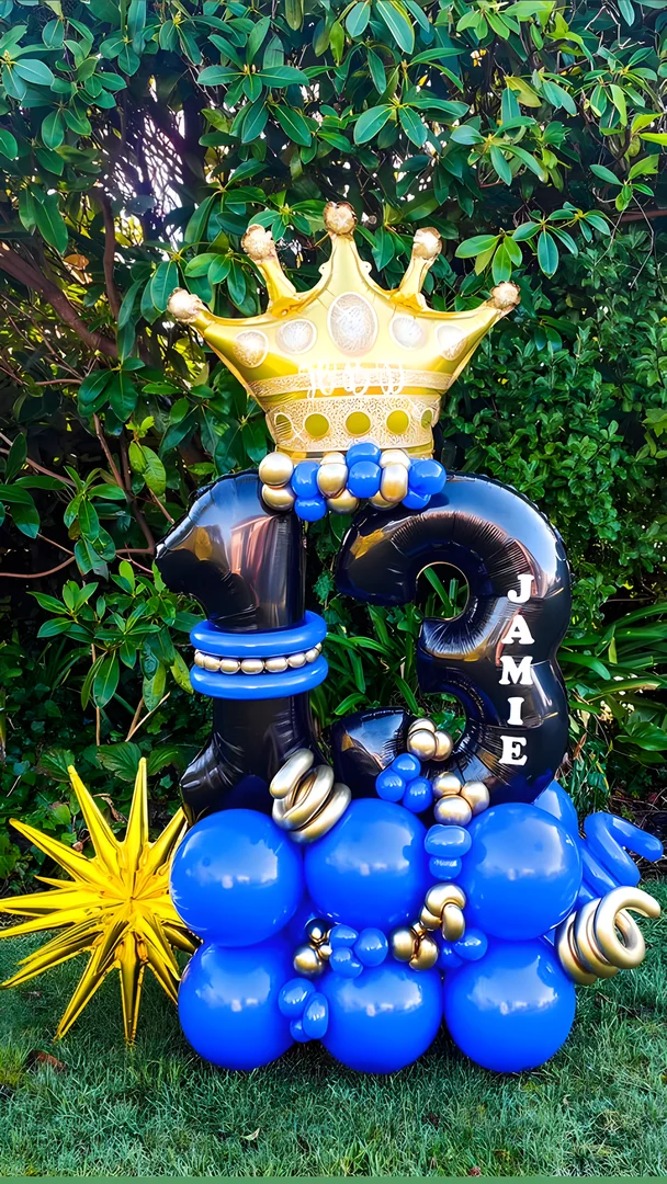 Black 13 foil numbers with the name Jamie, a gold crown topper and a gold starburst on a royal blue and gold balloon base